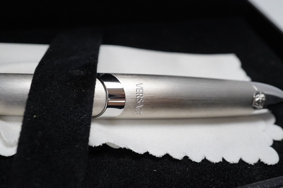 Two boxed pens; a Versace and a Cross, both with outer cardboard boxes. Condition - Versace pen good, display box good, outer box damaged. Cross pen good, ink bottle good, case damaged